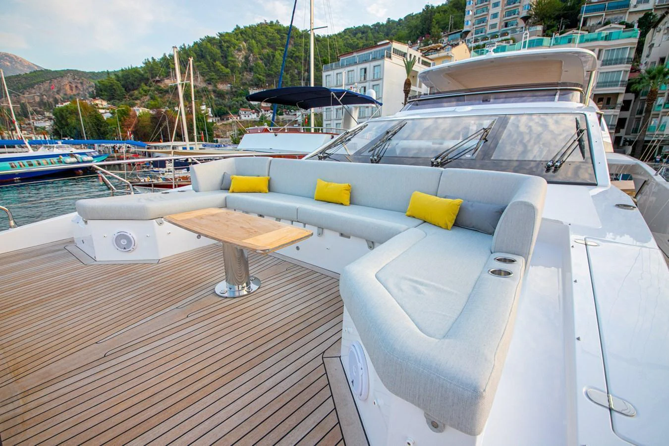 The spacious aft deck features a comfortable seating area with vibrant yellow cushions and a central table, perfect for outdoor relaxation. aboard NIRVANA BY THE SEA Yacht for Sale