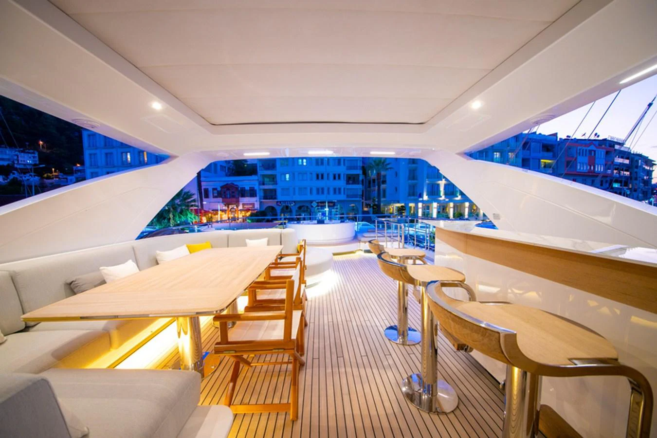 The aft deck features a stylish seating area with a dining table and bar stools, perfect for entertaining. aboard NIRVANA BY THE SEA Yacht for Sale