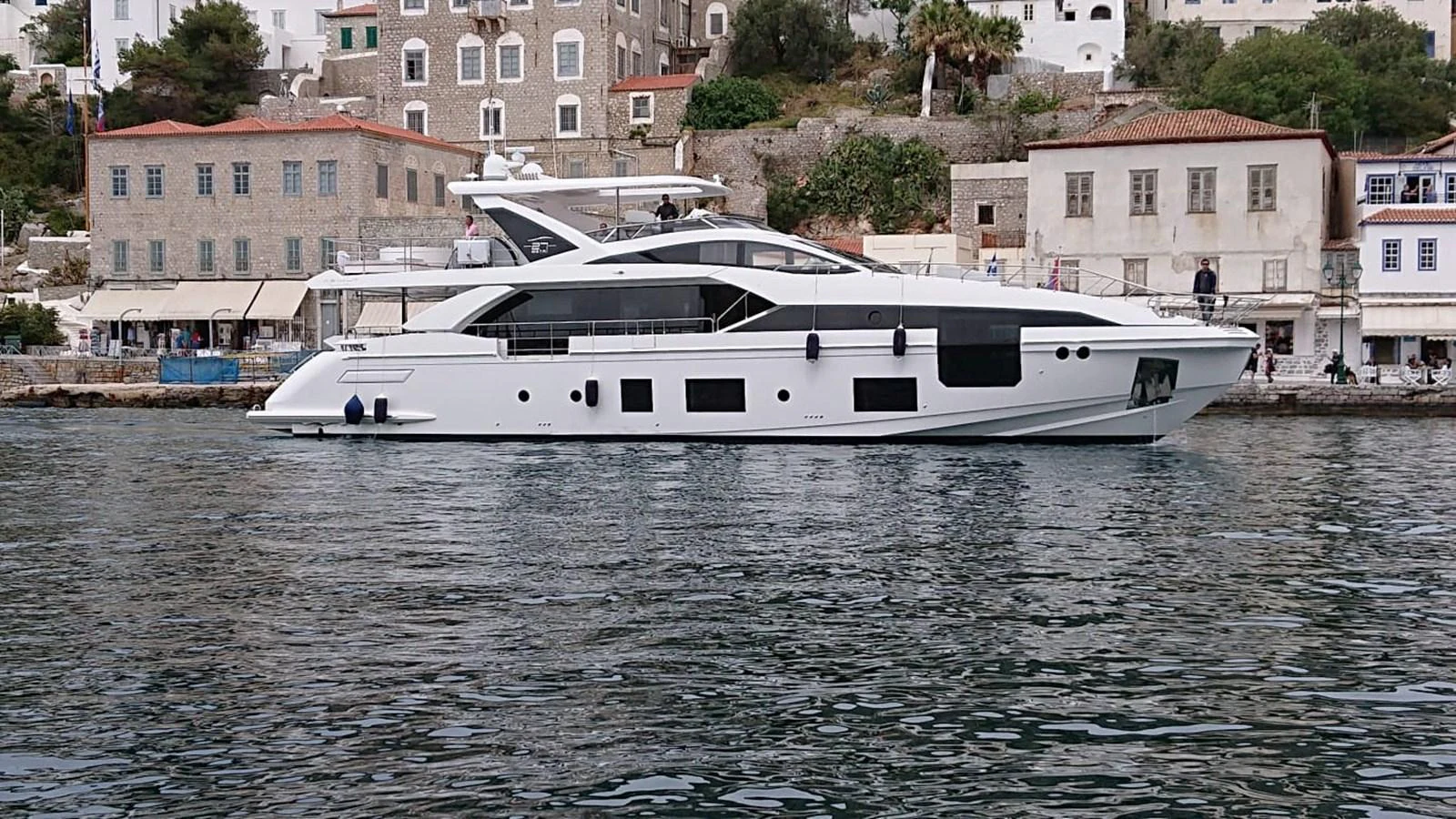 A sleek, modern yacht is docked near a charming coastal town, showcasing its elegant design and spacious layout. aboard NIRVANA BY THE SEA Yacht for Sale