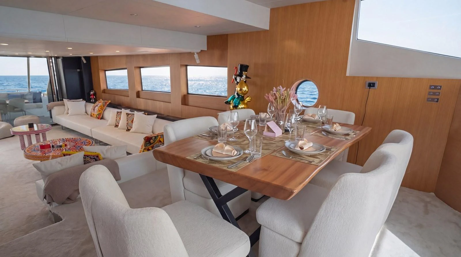 The yacht's salon features a stylish dining area with a wooden table and plush seating, complemented by a comfortable lounge area with large windows offering stunning sea views. aboard TAYGET Yacht for Sale
