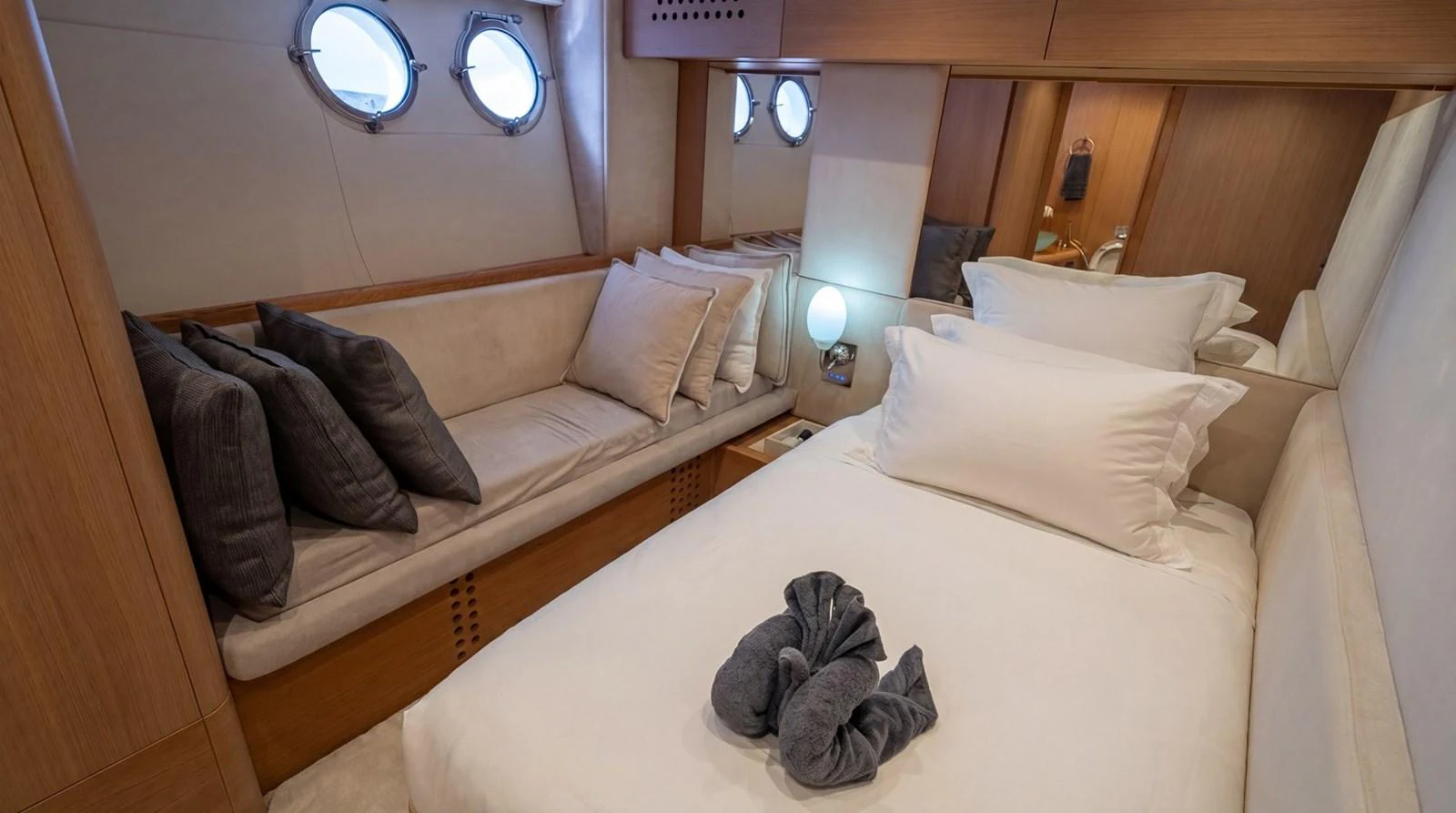 A cozy guest cabin featuring a single bed, a sofa, and porthole windows. aboard TAYGET Yacht for Sale