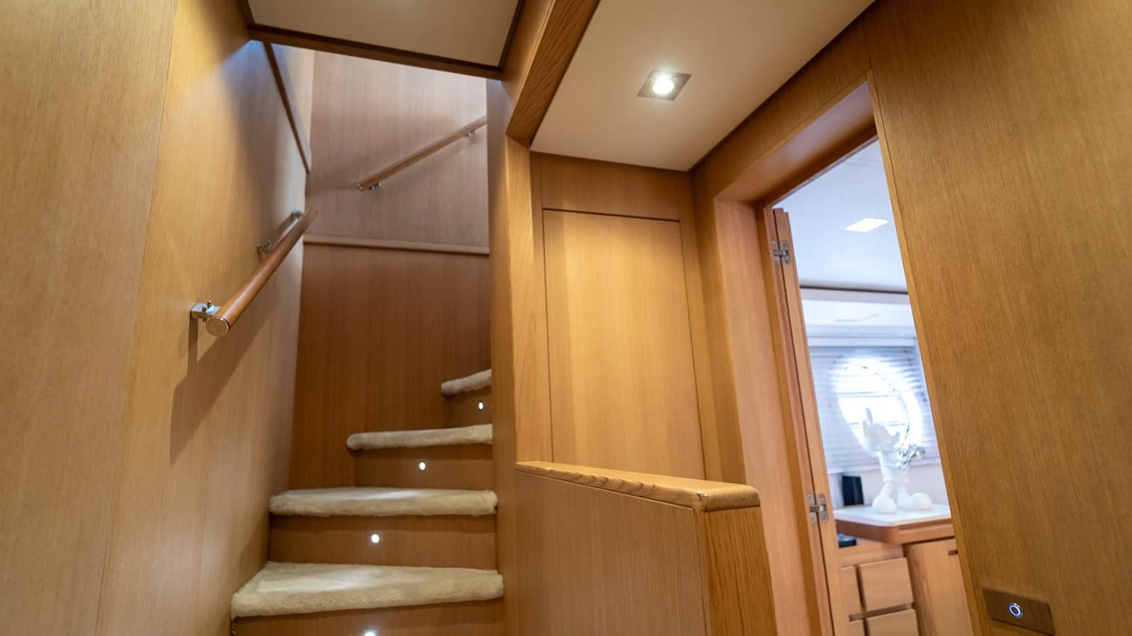 The image showcases a well-lit interior staircase with wooden paneling and carpeted steps. aboard TAYGET Yacht for Sale