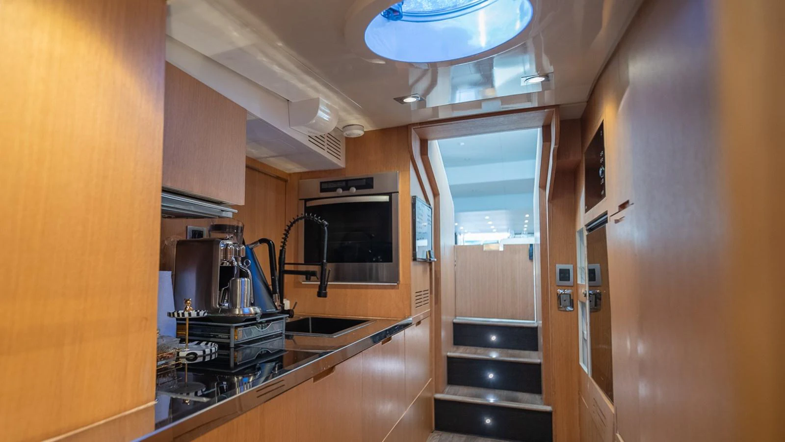 The yacht's galley features modern appliances and sleek wooden cabinetry, illuminated by natural light from a skylight. aboard TAYGET Yacht for Sale