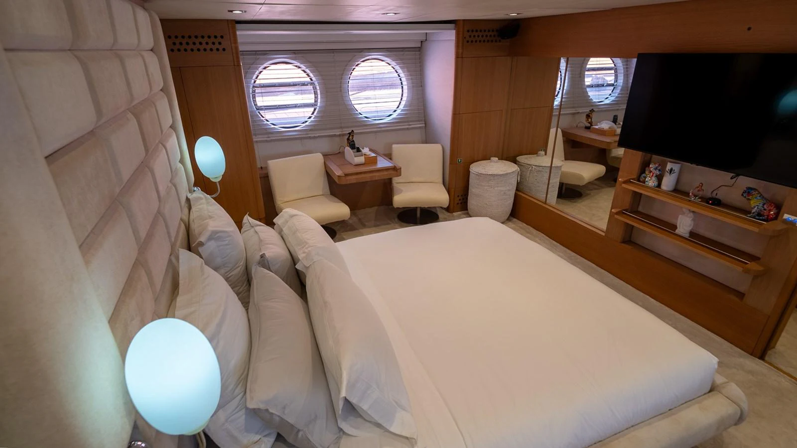 The stateroom features a plush bed, modern lighting, and a cozy seating area with porthole windows. aboard TAYGET Yacht for Sale