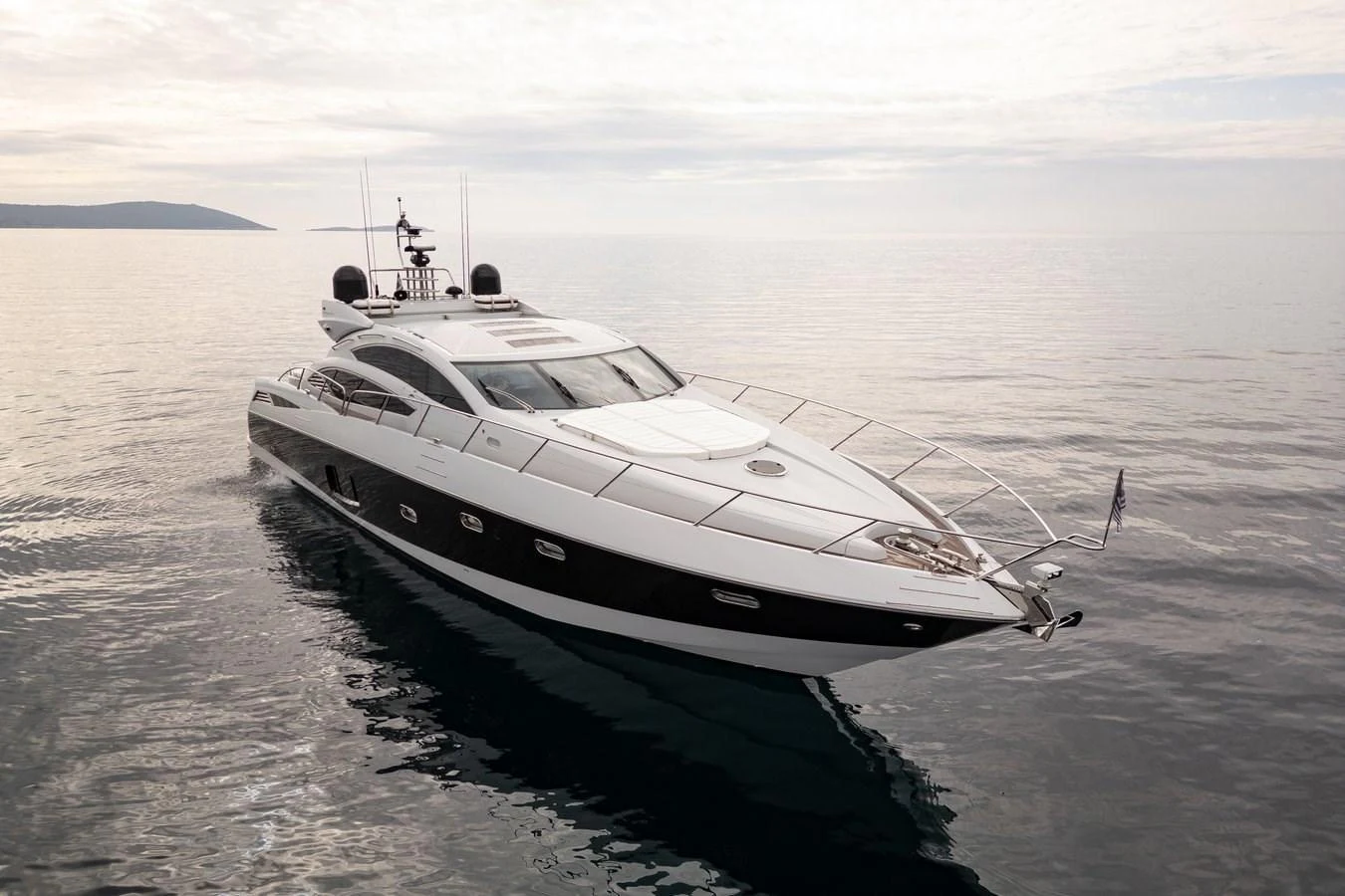 A sleek, modern yacht glides gracefully on calm waters under a cloudy sky. aboard M/Y TITAN Yacht for Sale