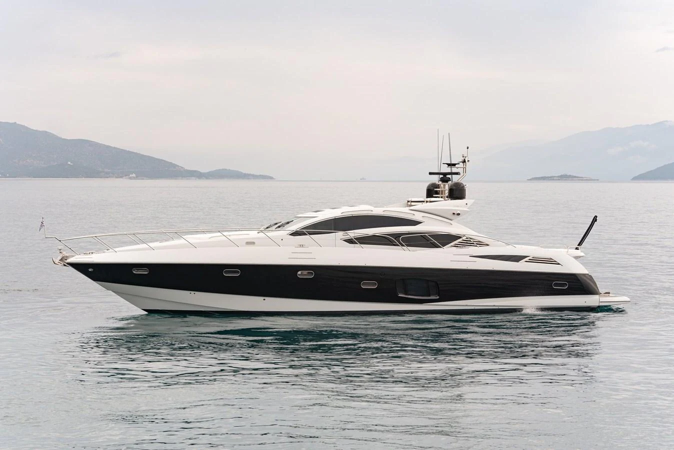 A sleek and modern yacht glides gracefully on calm waters with a scenic backdrop. aboard M/Y TITAN Yacht for Sale