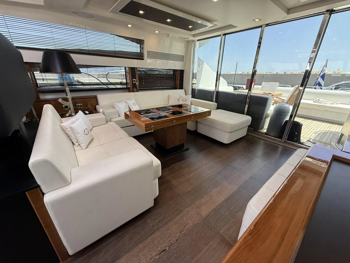 The salon features luxurious white seating and a wooden table, with ample natural light streaming through large windows. aboard M/Y TITAN Yacht for Sale
