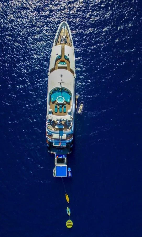 Aerial view of a luxurious yacht anchored in deep blue waters, showcasing its expansive decks and water toys. aboard HOLIDAY Yacht for Sale