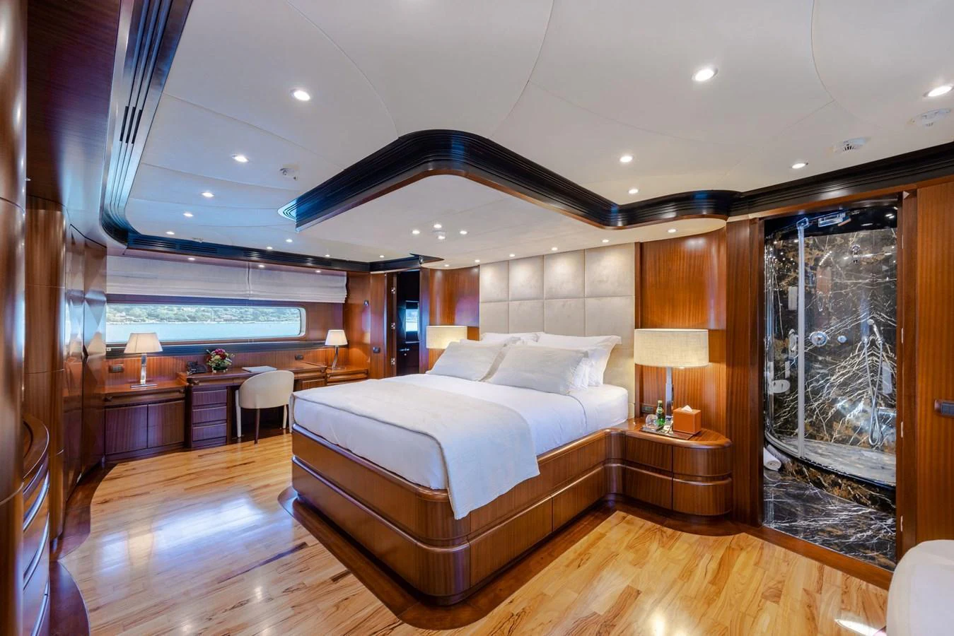 The master stateroom features a luxurious bed, elegant wood finishes, and ample natural light. aboard HOLIDAY Yacht for Sale