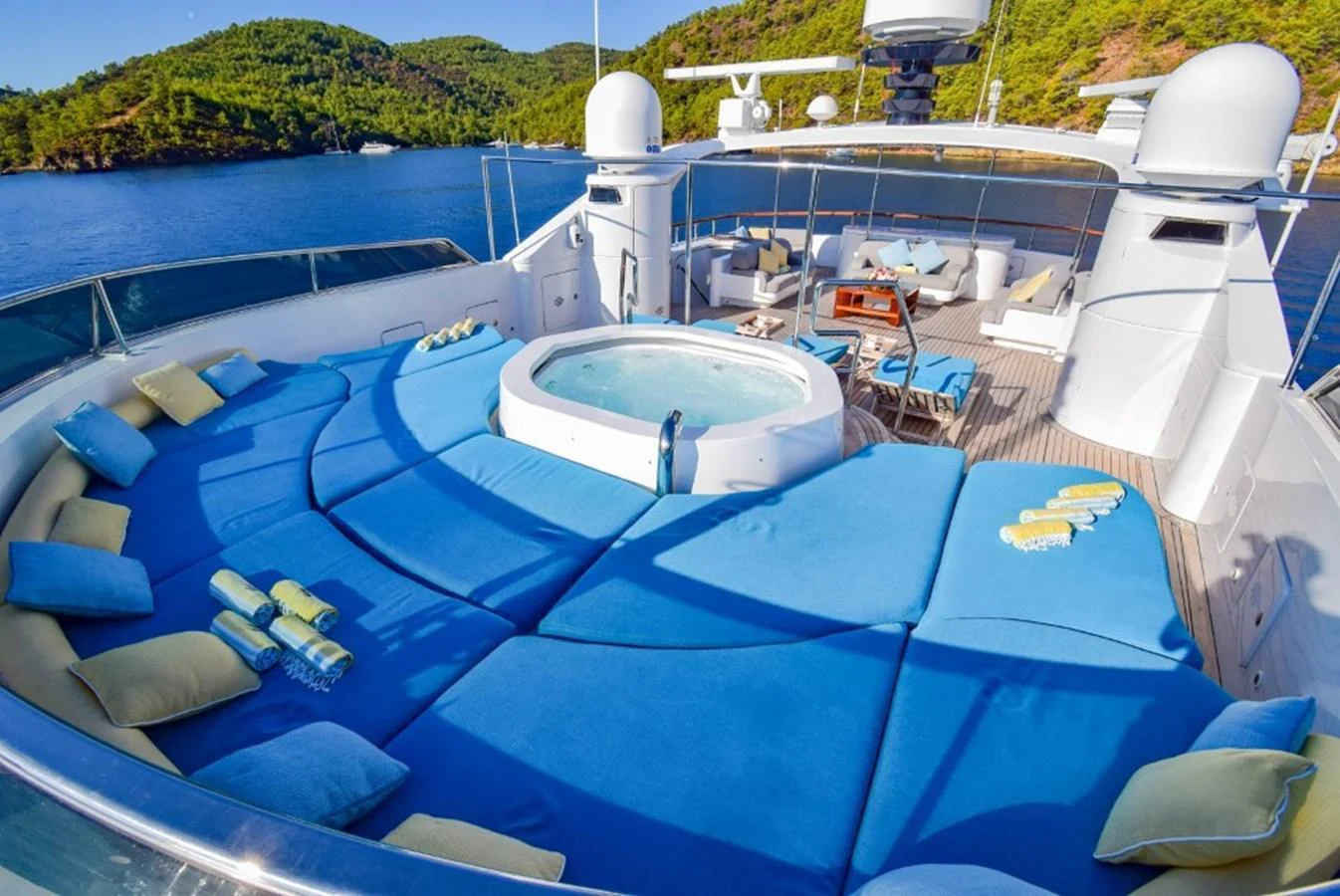 The sundeck features a luxurious jacuzzi surrounded by plush blue sun pads, offering a perfect relaxation spot with stunning views. aboard HOLIDAY Yacht for Sale