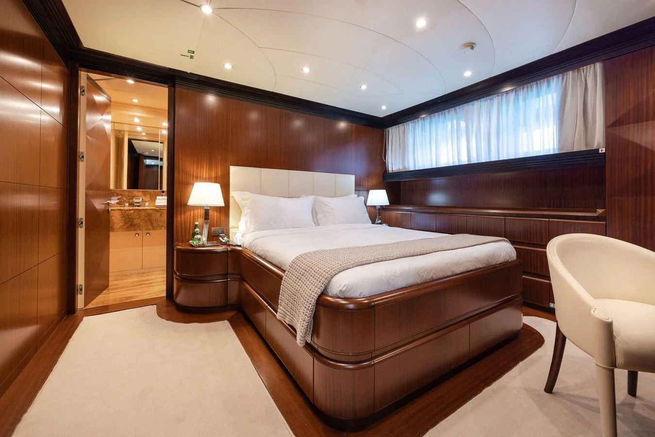The master stateroom features a luxurious bed with elegant wood paneling and soft lighting. aboard HOLIDAY Yacht for Sale