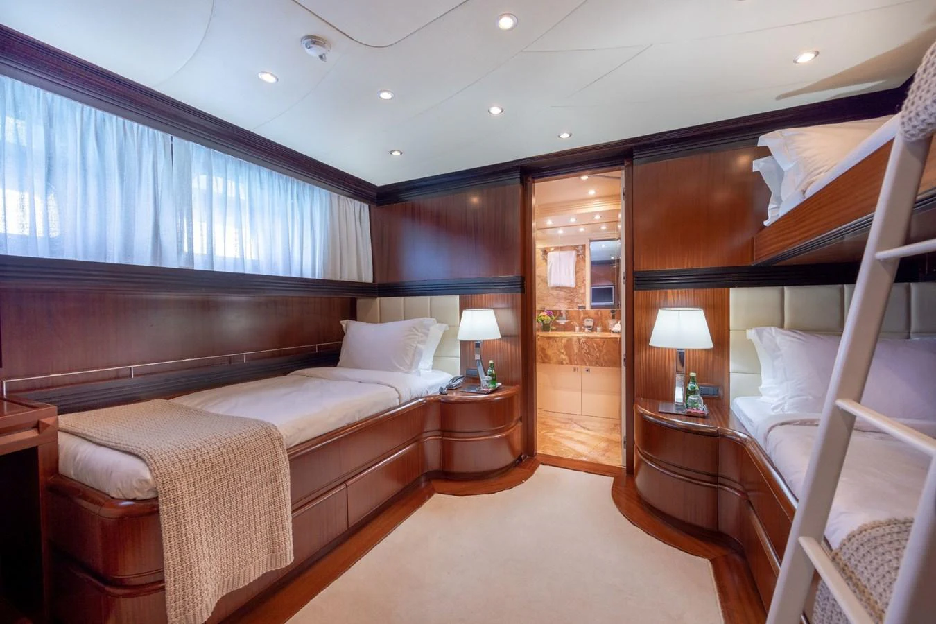 The guest stateroom features twin beds, warm wood paneling, and soft lighting for a cozy retreat. aboard HOLIDAY Yacht for Sale