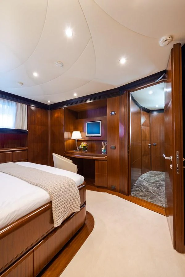 The stateroom features elegant wood paneling, a comfortable bed, and a cozy workspace. aboard HOLIDAY Yacht for Sale