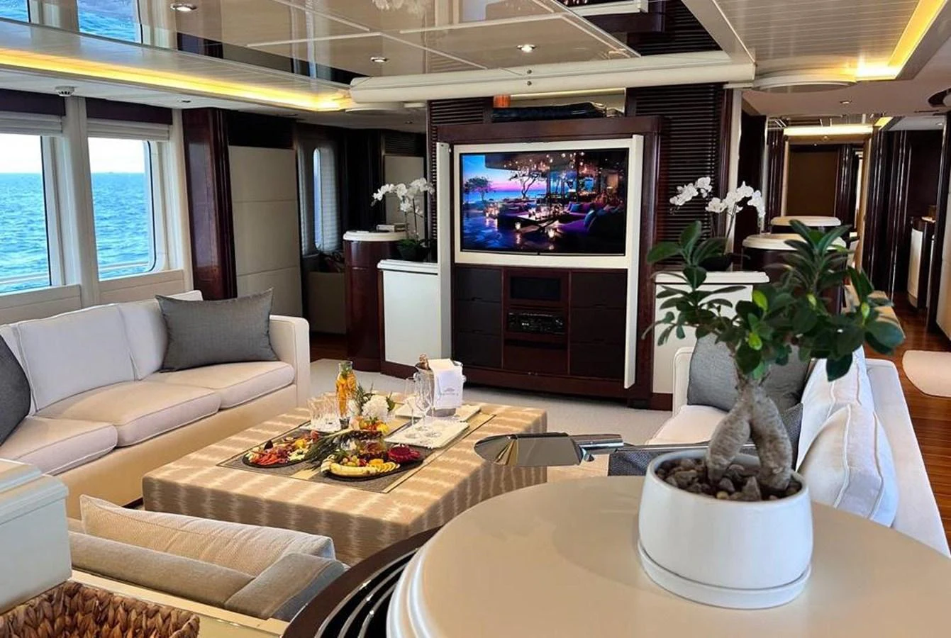The luxurious salon features elegant seating, a large TV, and a beautifully set table, offering a comfortable and stylish space for relaxation. aboard PRINCESS TOO Yacht for Sale