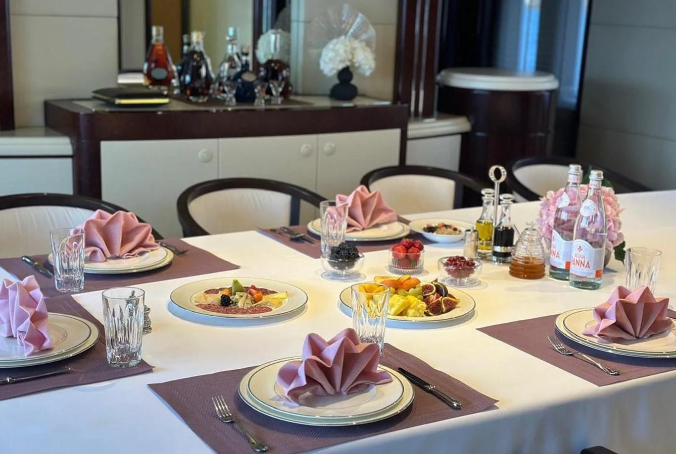 The yacht's dining area is elegantly set for a meal, featuring fine tableware and a sophisticated ambiance. aboard PRINCESS TOO Yacht for Sale