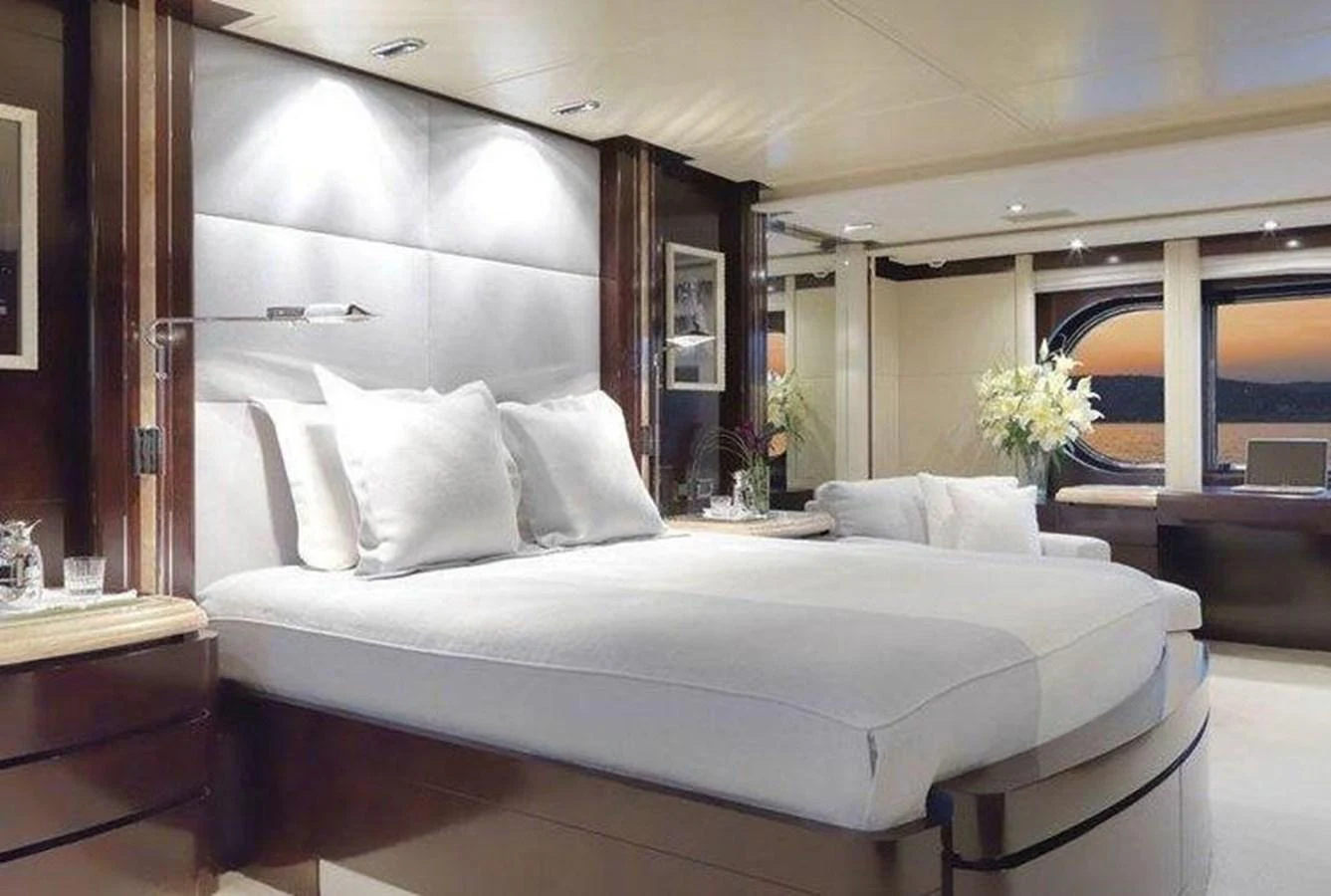 The master stateroom features a luxurious bed and elegant decor with a stunning view through large windows. aboard PRINCESS TOO Yacht for Sale