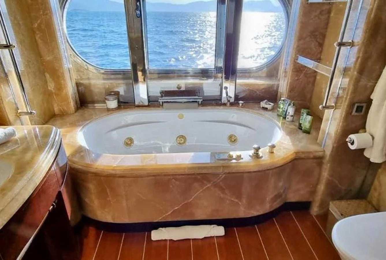 The luxurious bathroom features a large bathtub with a scenic ocean view through the windows. aboard PRINCESS TOO Yacht for Sale