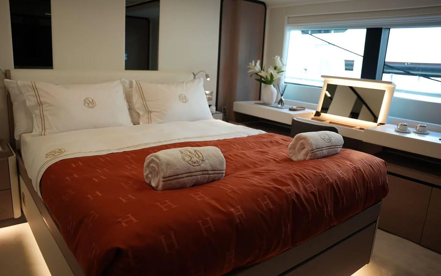 A luxurious stateroom featuring a plush bed with elegant linens and a well-lit vanity area. aboard GEULUNEL Yacht for Sale