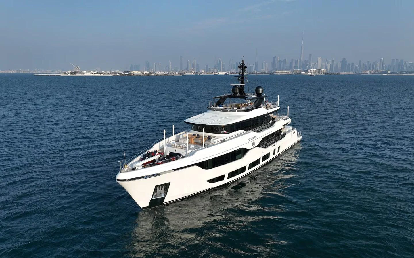 A sleek, modern yacht cruising on calm waters with a city skyline in the background. aboard GEULUNEL Yacht for Sale
