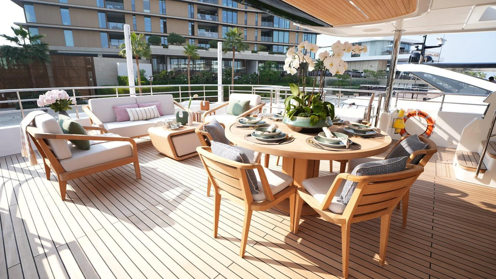 The aft deck features an elegant outdoor dining area with comfortable seating and lush greenery. aboard GEULUNEL Yacht for Sale