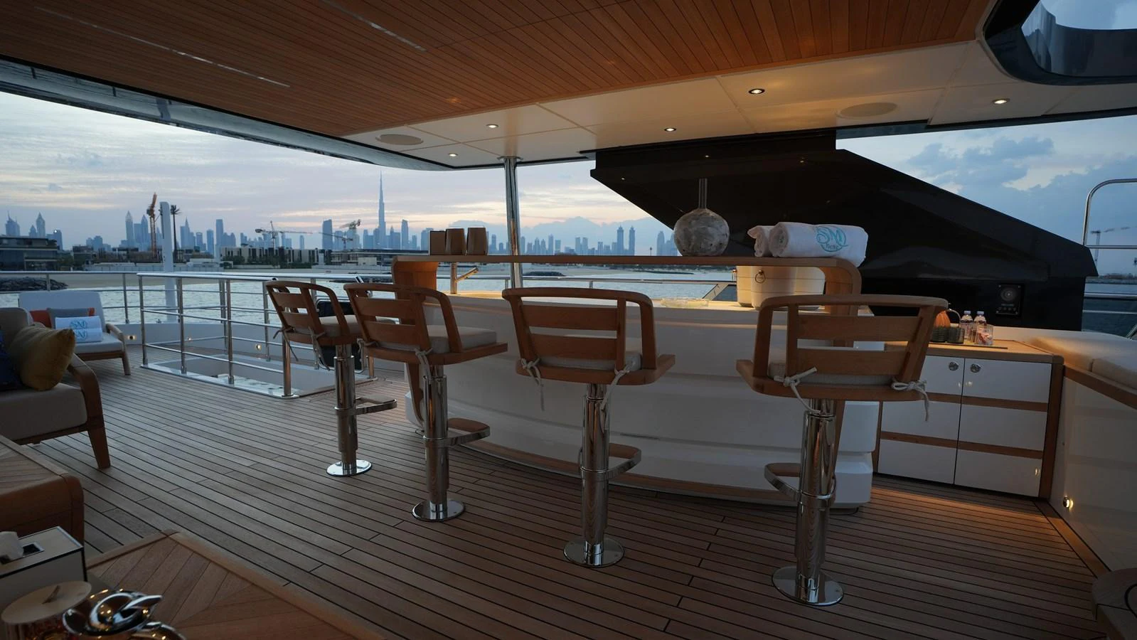 The yacht features a stylish bar area with modern seating and a view of the city skyline. aboard GEULUNEL Yacht for Sale