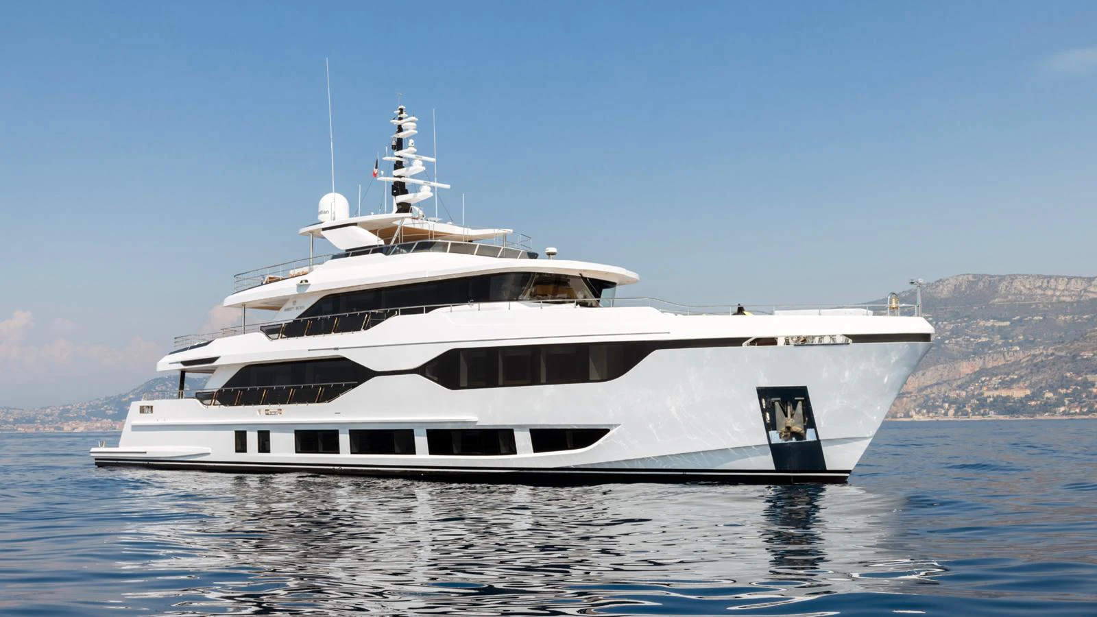 A sleek, modern yacht cruising on calm waters with a scenic coastal backdrop. aboard GEULUNEL Yacht for Sale