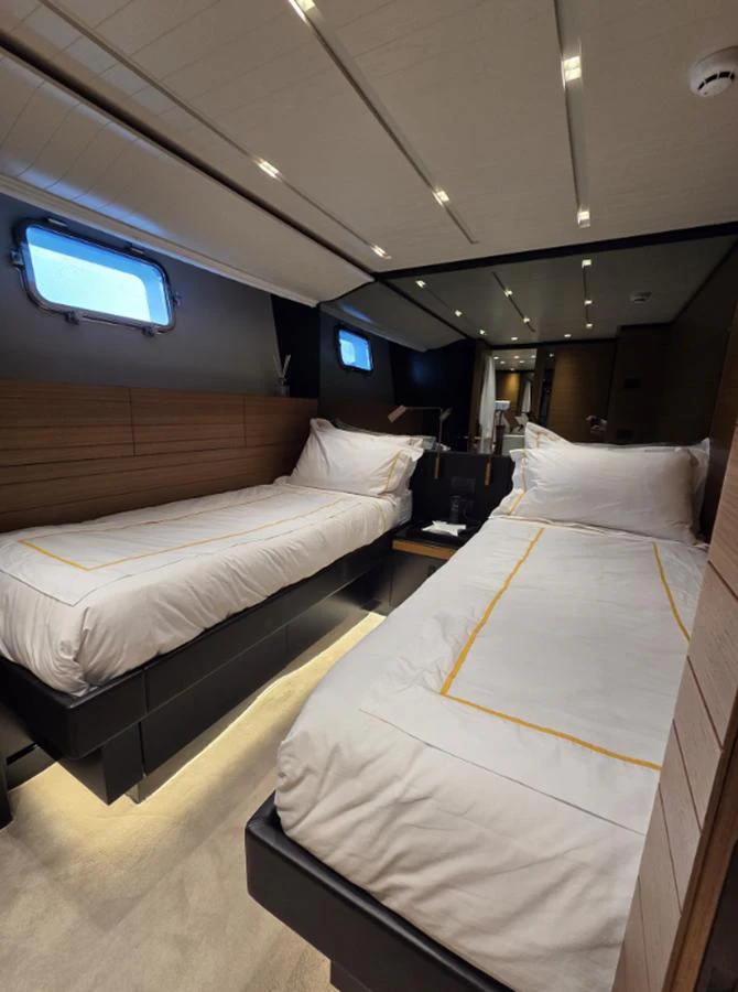 The twin stateroom features two comfortable single beds with elegant bedding and modern lighting. aboard SOLEDO Yacht for Sale