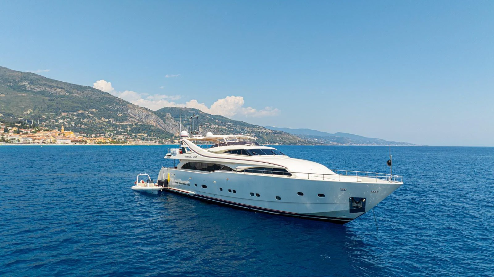 A sleek and modern yacht cruises gracefully on the open sea with a picturesque coastal backdrop. aboard CHAMPAGNE AND CAVIAR Yacht for Sale