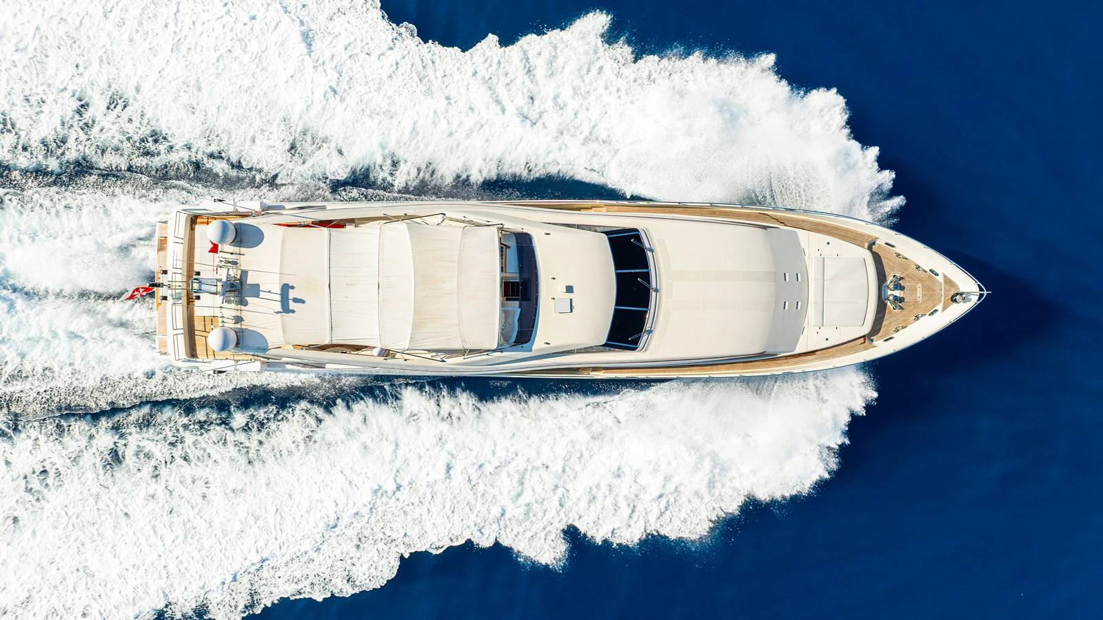 An aerial view of a sleek yacht cruising through the water, leaving a trail of white waves behind. aboard CHAMPAGNE AND CAVIAR Yacht for Sale