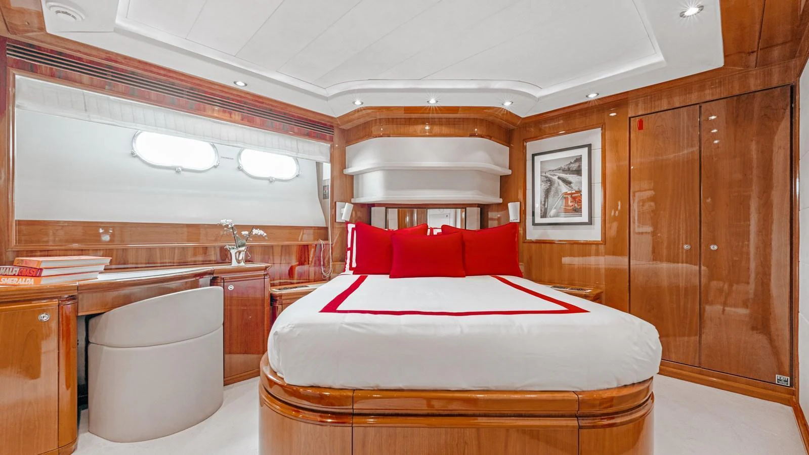 The master stateroom features elegant wood paneling and a luxurious bed with red accents. aboard CHAMPAGNE AND CAVIAR Yacht for Sale