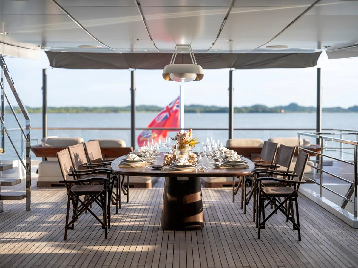 The aft deck features an elegant dining area with a beautifully set table, perfect for alfresco meals with a view. aboard ANNABELLA Yacht for Sale