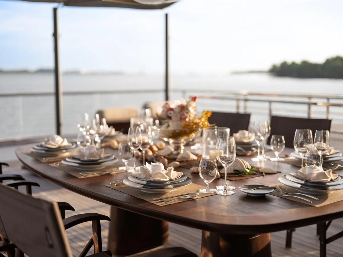 An elegant alfresco dining area set for a meal, offering stunning views of the water. aboard ANNABELLA Yacht for Sale