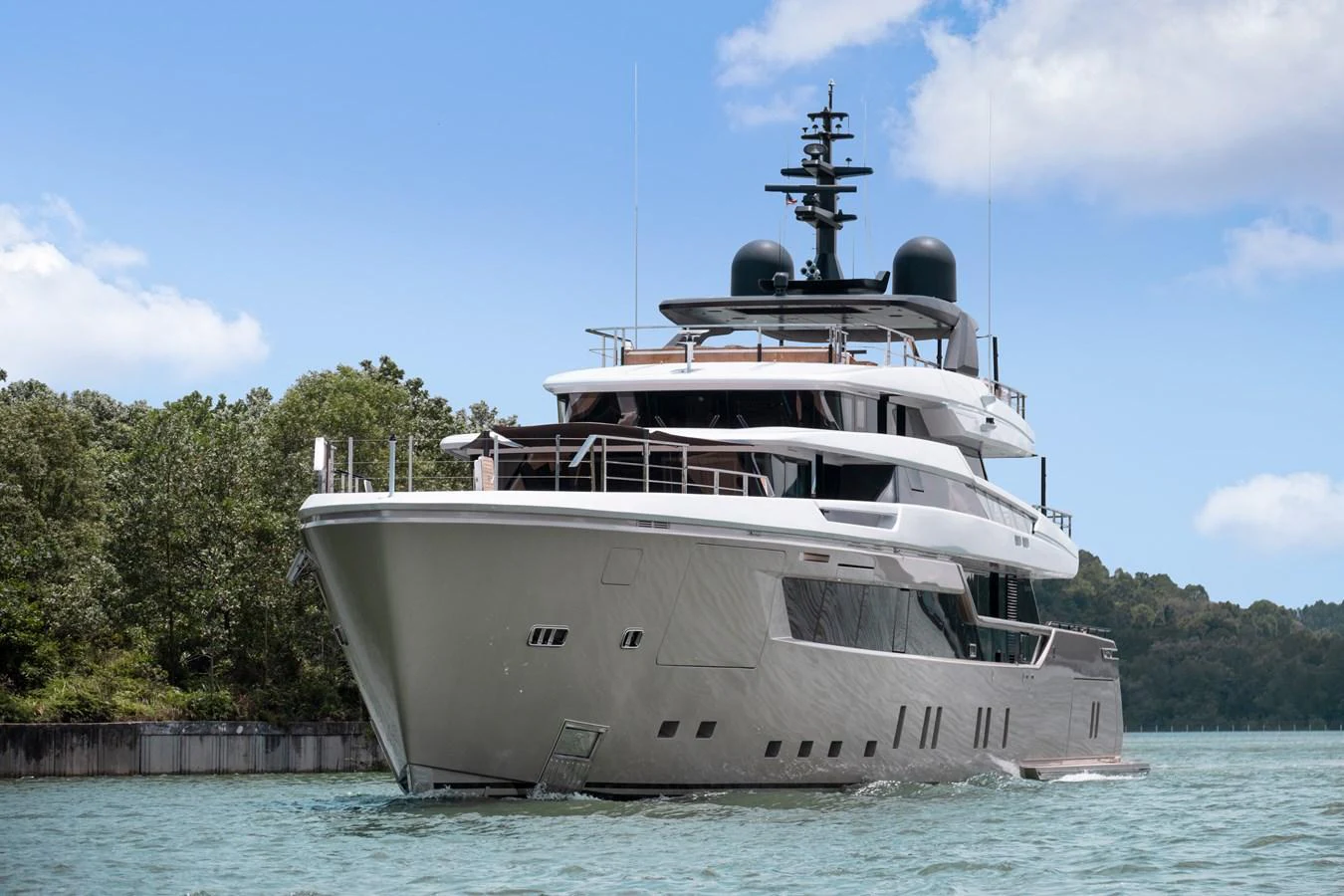 A sleek and modern yacht cruising on calm waters with a lush green shoreline in the background. aboard ANNABELLA Yacht for Sale