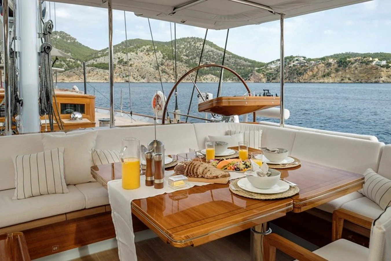 The aft deck features a beautifully set dining table with a picturesque view of the surrounding waters. aboard APSARA Yacht for Sale