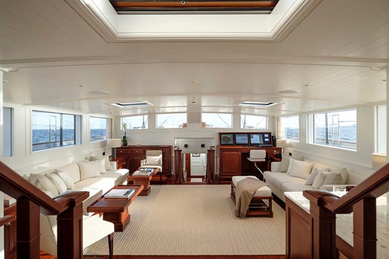 The spacious salon features elegant wood furnishings and ample natural light from large windows. aboard APSARA Yacht for Sale