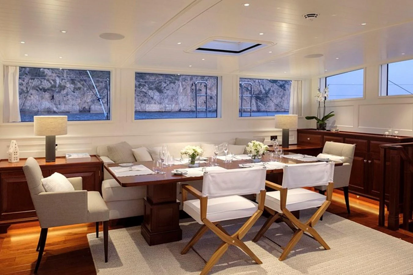 The yacht's dining area features elegant seating and a beautifully set table, with large windows offering stunning views. aboard APSARA Yacht for Sale