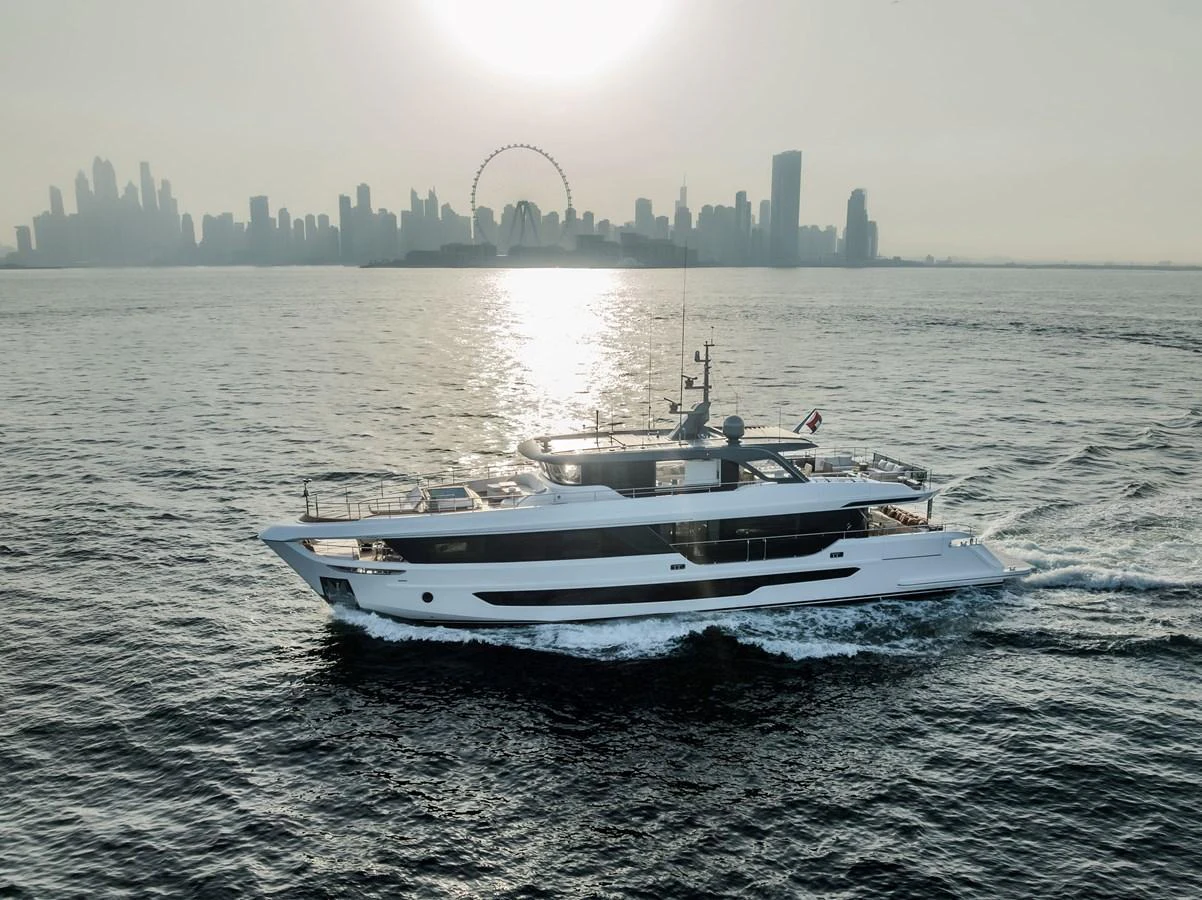 A sleek yacht cruises through calm waters with a city skyline in the background. aboard 100 TERRACE ON-ORDER Yacht for Sale
