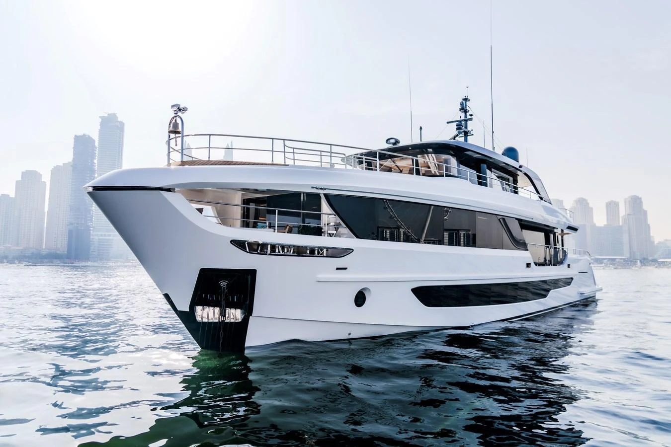 A sleek and modern yacht glides gracefully on calm waters with a city skyline in the background. aboard 100 TERRACE ON-ORDER Yacht for Sale