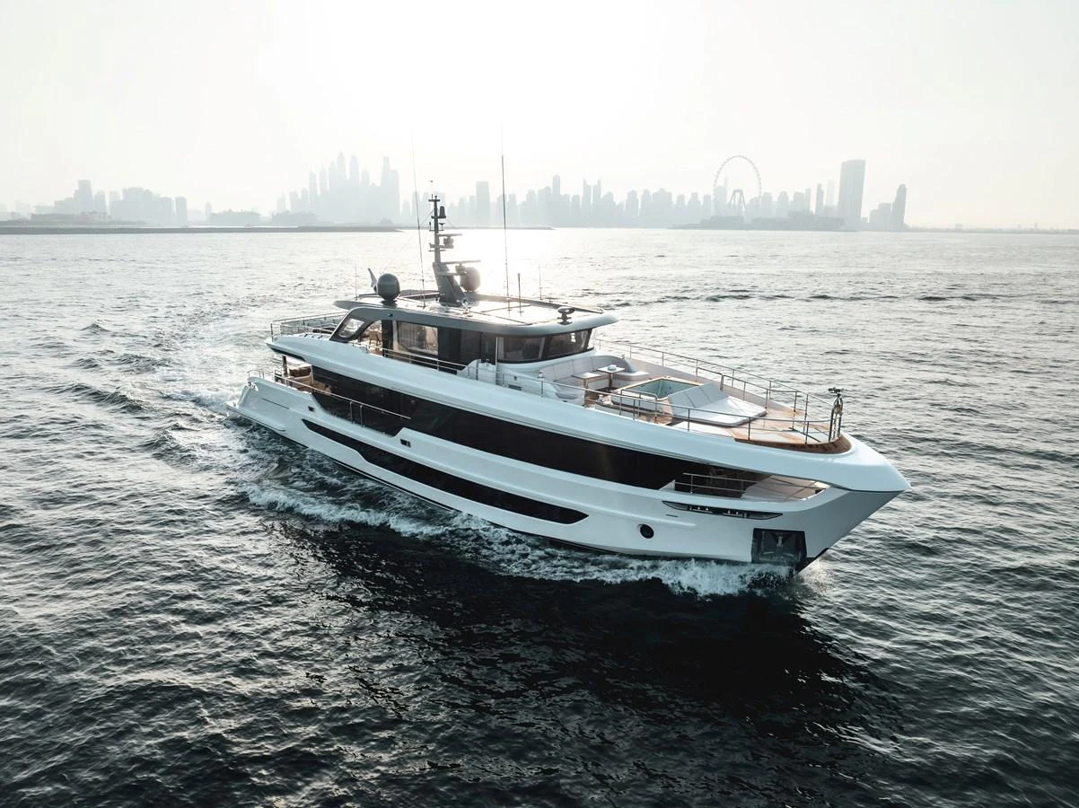 A sleek and modern yacht cruises through calm waters with a city skyline in the background. aboard 100 TERRACE ON-ORDER Yacht for Sale
