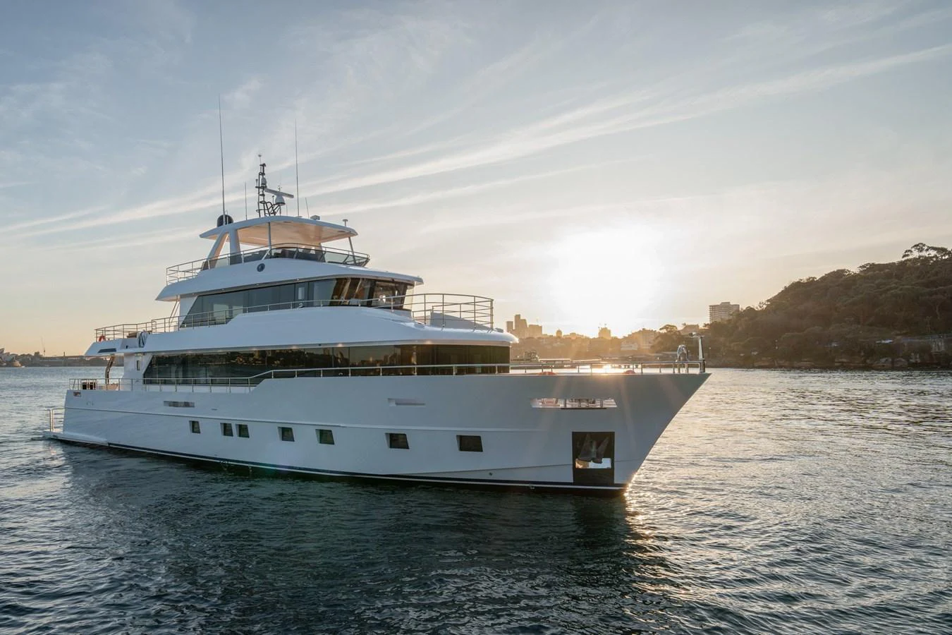 A sleek and modern yacht glides gracefully on the water at sunset. aboard NOMAD 101 ON-ORDER Yacht for Sale