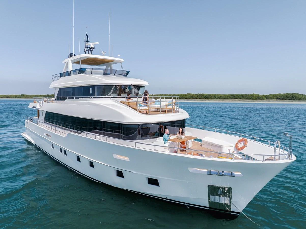 A luxurious yacht cruising on calm waters with people enjoying the spacious deck areas. aboard NOMAD 101 ON-ORDER Yacht for Sale
