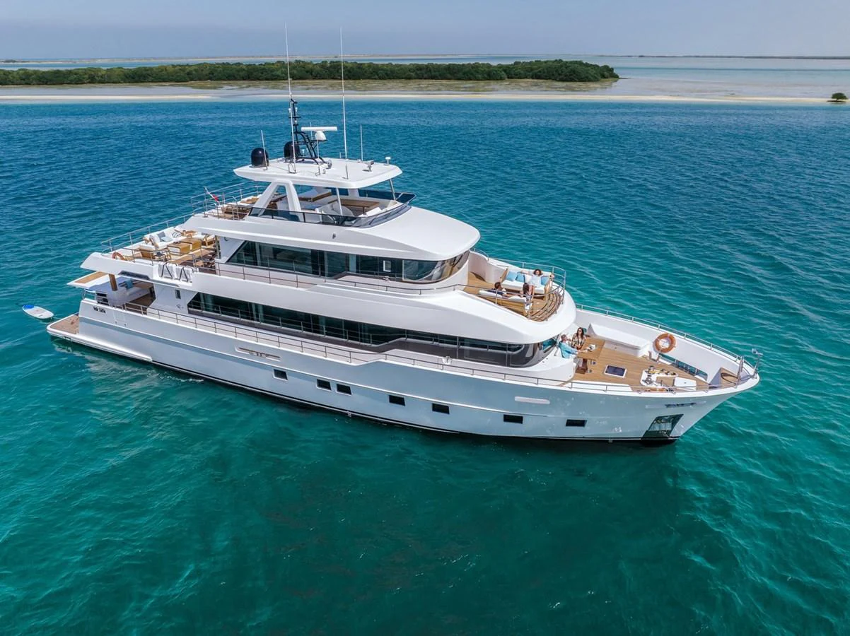 A luxurious yacht cruising on clear blue waters with a scenic island in the background. aboard NOMAD 101 ON-ORDER Yacht for Sale