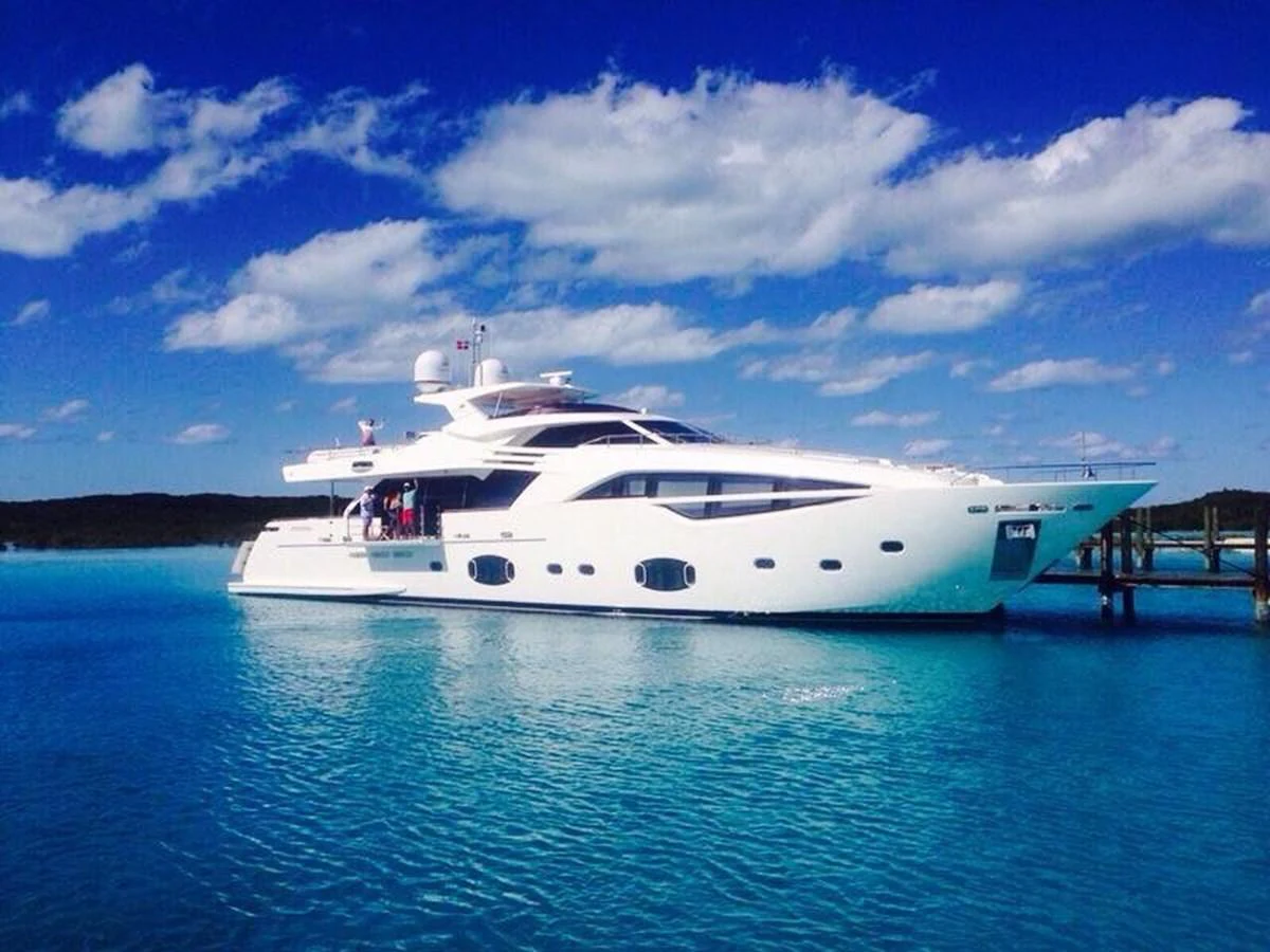 A sleek, modern yacht is anchored in crystal-clear blue waters under a bright, sunny sky. aboard SHA SHA SHA IV Yacht for Sale