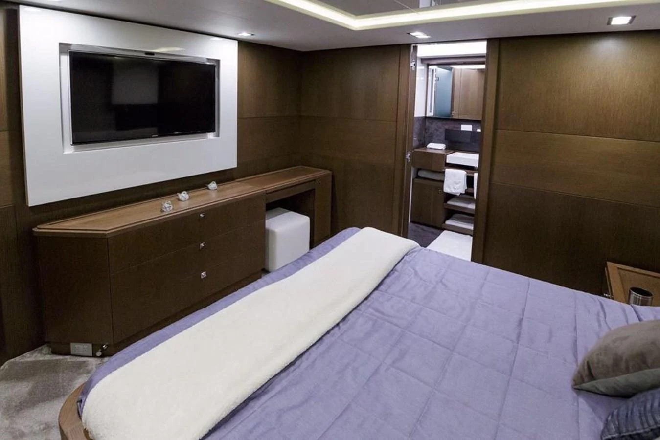 The stateroom features a luxurious bed, a flat-screen TV, and elegant wood finishes. aboard SHA SHA SHA IV Yacht for Sale