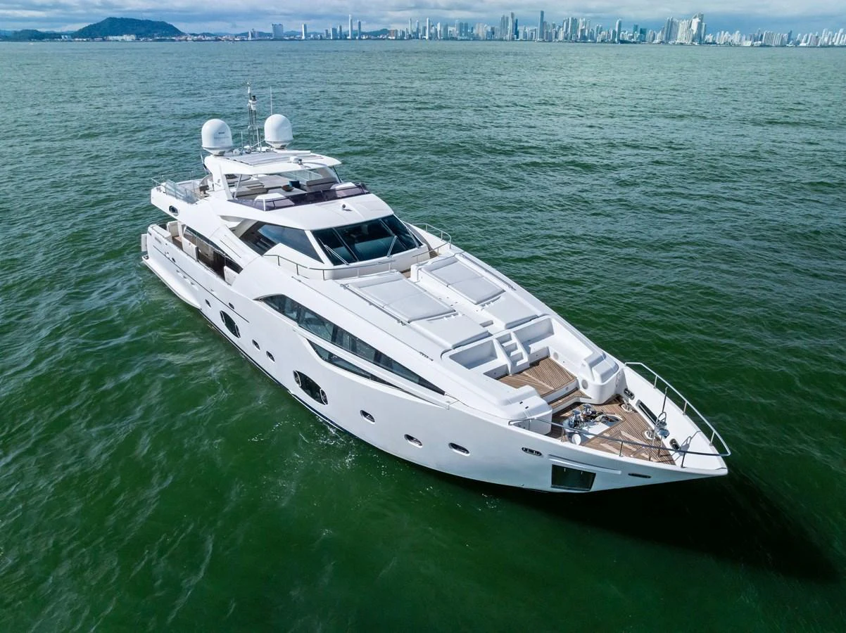 A sleek and modern yacht cruising on calm waters with a cityscape in the background. aboard SHA SHA SHA IV Yacht for Sale