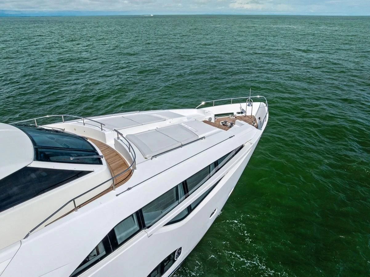 A sleek yacht glides gracefully over calm green waters, showcasing its modern design and spacious deck. aboard SHA SHA SHA IV Yacht for Sale