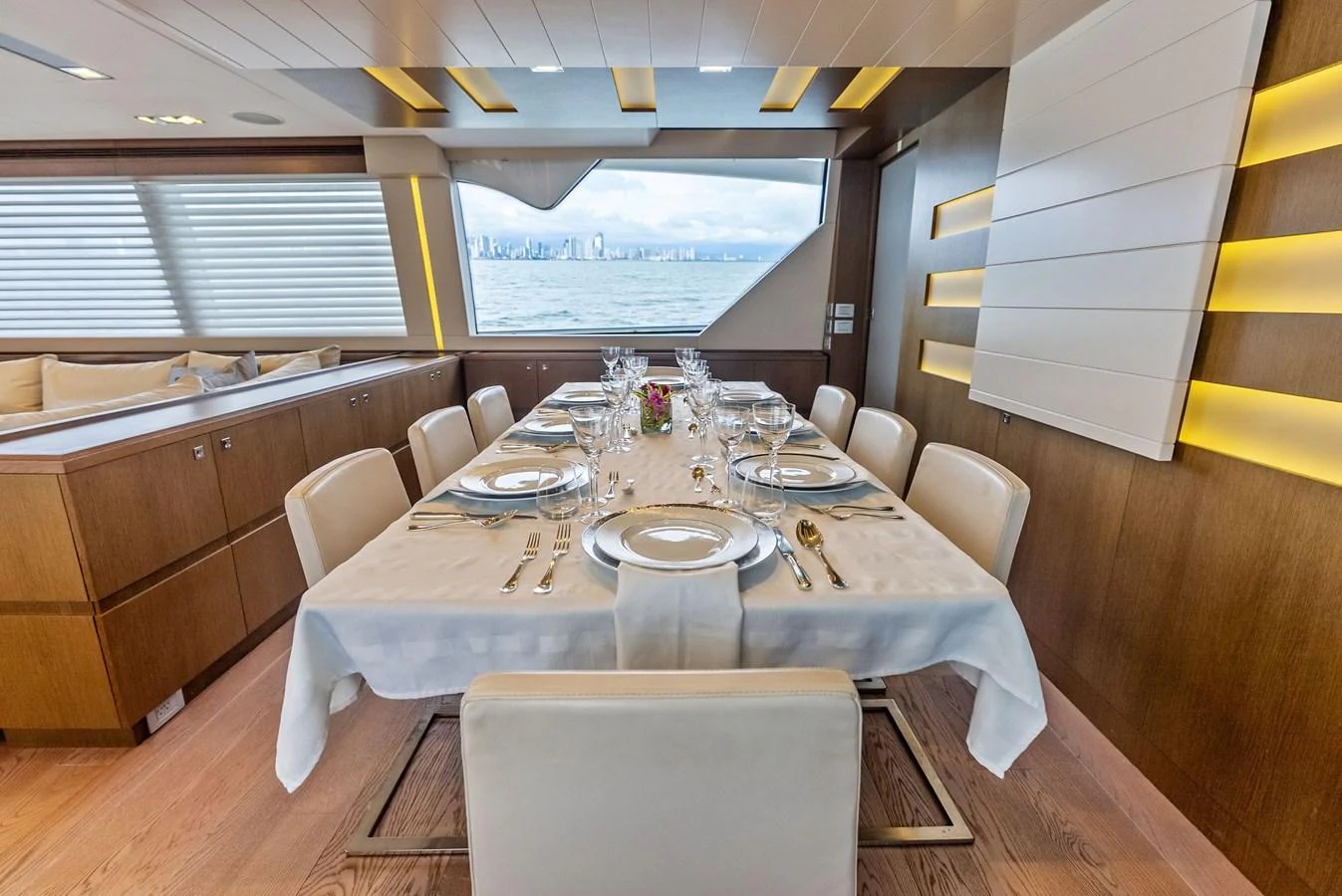 The yacht's dining area features a beautifully set table with a view of the sea through large windows. aboard SHA SHA SHA IV Yacht for Sale