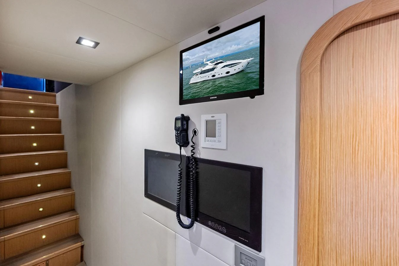 The interior features a staircase with ambient lighting and a wall-mounted television displaying a yacht image. aboard SHA SHA SHA IV Yacht for Sale