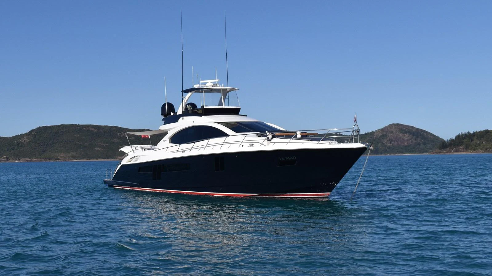 A sleek yacht glides gracefully on calm blue waters with a scenic backdrop. aboard LA MAR Yacht for Sale
