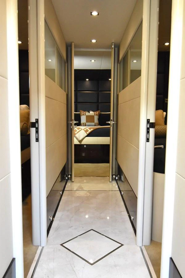 A luxurious hallway leads to a cozy stateroom with plush bedding. aboard LA MAR Yacht for Sale